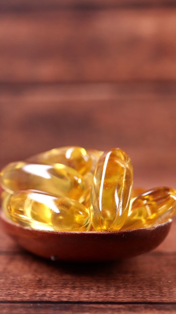 Close-up of Golden Fish Oil Softgels on a Wooden Spoon