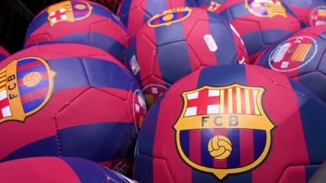 soccer balls decorated with barcelona football team colors and its insignia for sale at an official merchandise store