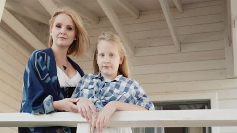 Portrait-of-a-mother-with-her-daughter-on-the-doorstep-of-their-wooden-house