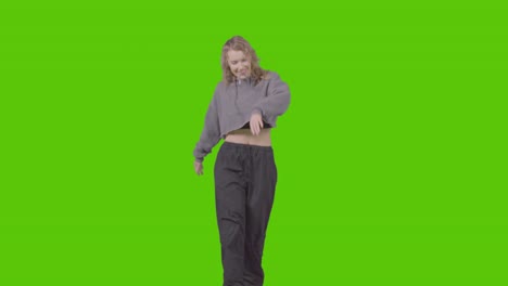 full length studio shot of young woman having fun dancing against green screen 3