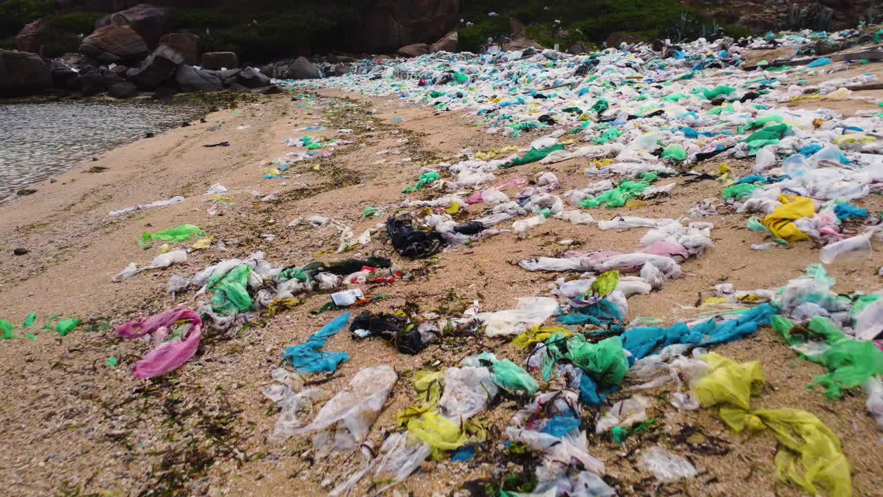 베트남 해변 모래 위의 플라스틱 쓰레기 위로 낮고 빠른 공중 비행