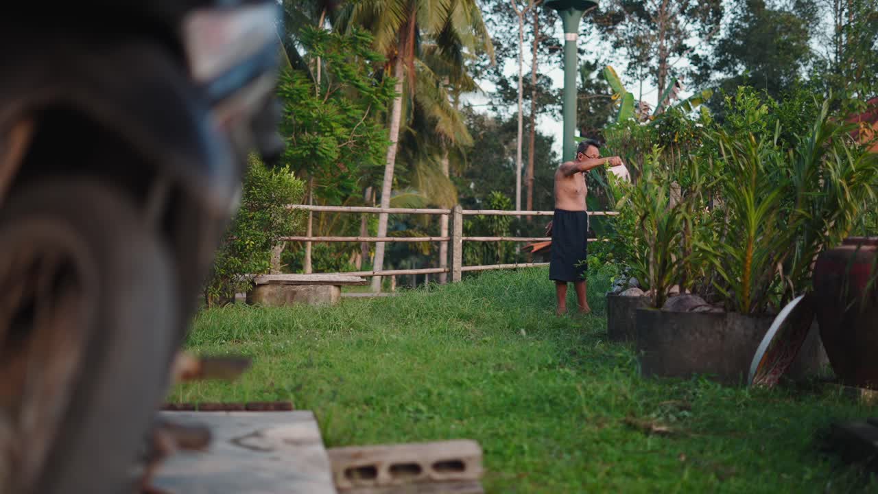 Man Watering Plants in a Tropical Garden