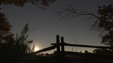 el lapso de tiempo de la hermosa salida de la luna, luna llena sobre la vieja valla de la granja