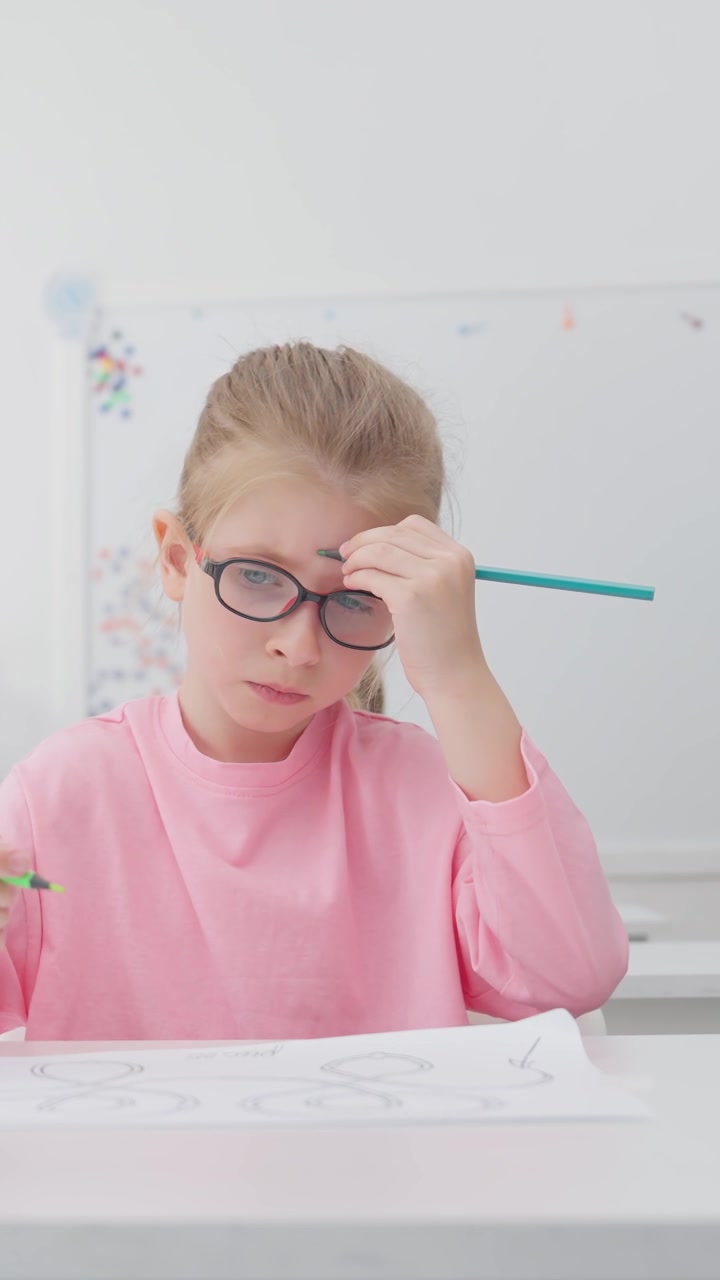 Giovane ragazza concentrata con gli occhiali che disegna e impara in un'aula.