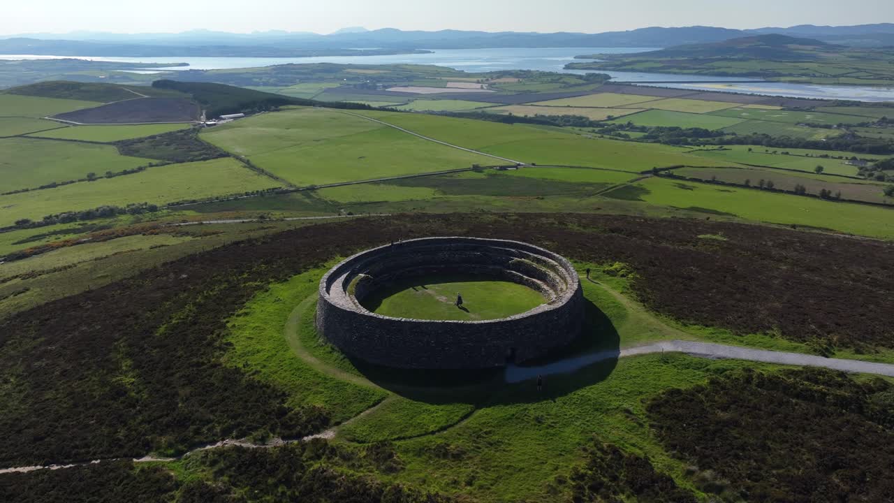 Grianan of Aileach, County Donegal, Ireland, June 2023. Drone counter clockwise orbit of tourists visiting the iconic Greenan Stone Fort surrounded by countryside atop a hill above Drongawn Lough.