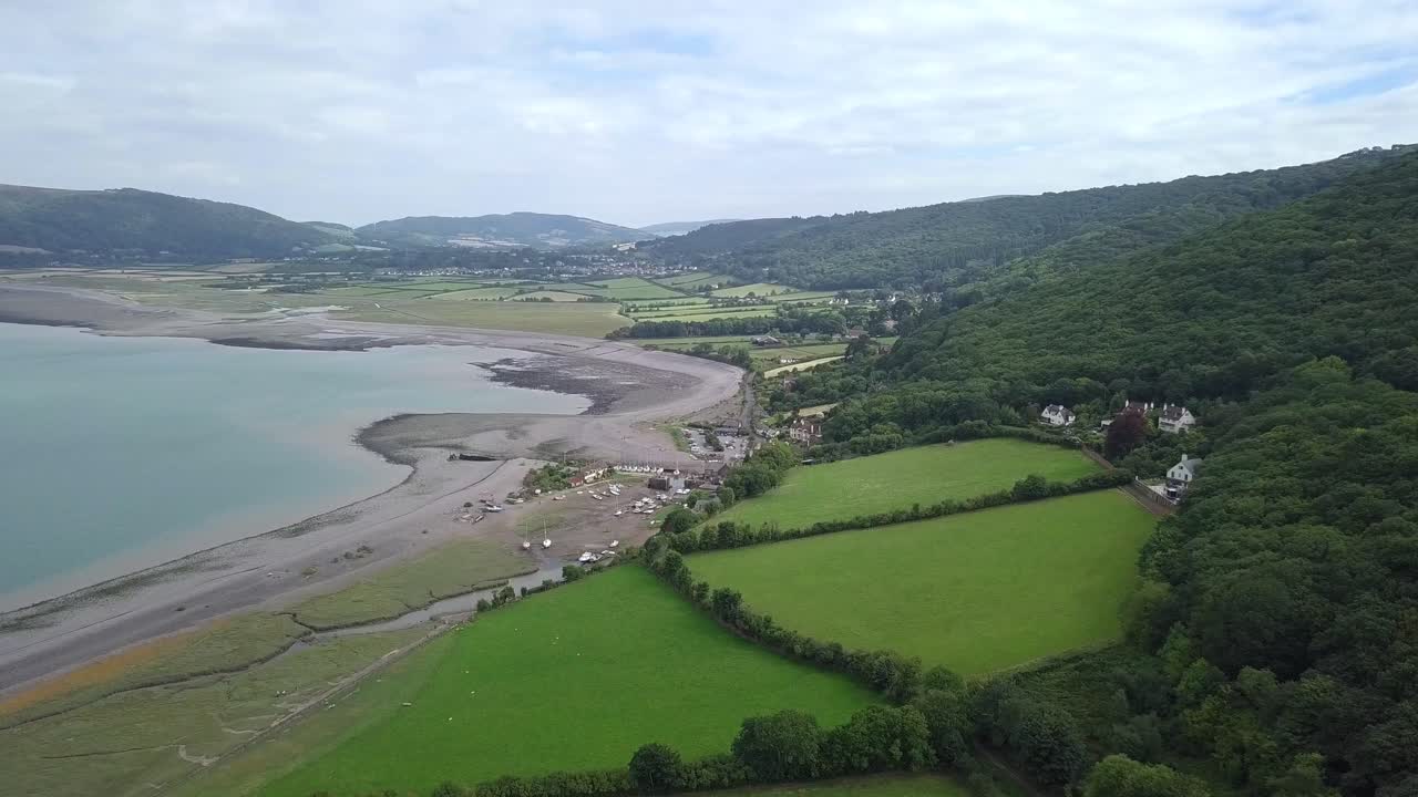 Aerial view of a coastal landscape with an estuary, fields, and mountains