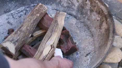 man placing igniters on wood for a barbeque