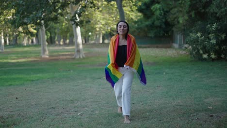 woman walking with rainbow pride flag in a park