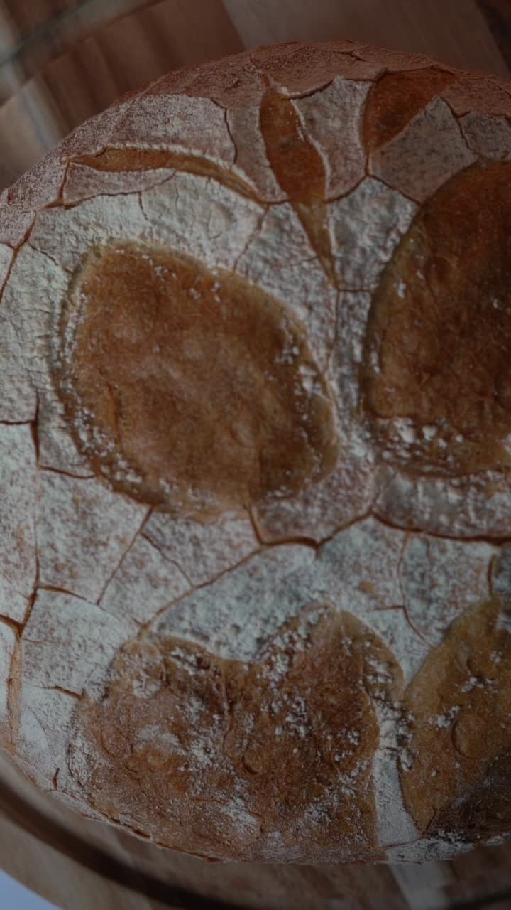 View of a rustic loaf of bread with a cracked, golden crust and flour-dusted surface, close up shot