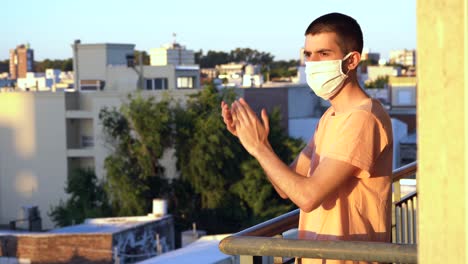 young man applauding health workers from the balcony at sunset