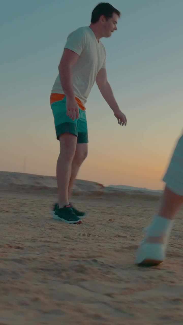 Woman playing soccer on the beach at sunset