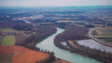 an aerial view of the patchwork of fields, small towns, forests, and a solar farm on the banks of the river in rural germany