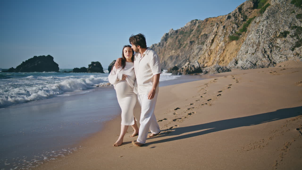 아이를 기다리는 부부는 여름 가족 휴가에서 해변을 고 있습니다. 미래의 부모