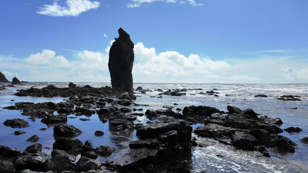 las mareas de primavera llenan suavemente la playa pedregosa bajo una gran pila de mar en la playa de ballydwane en waterford, irlanda.