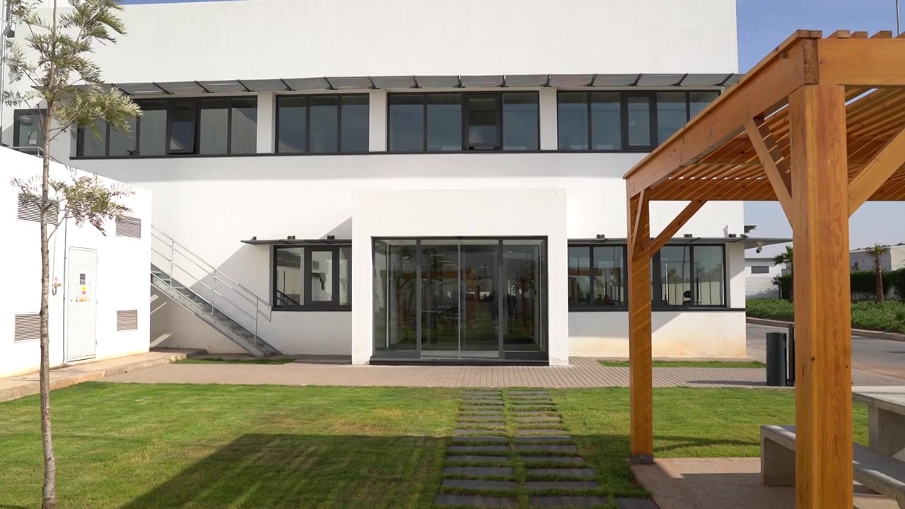 Esterno di un moderno edificio per uffici bianco con pergole in legno e prato.