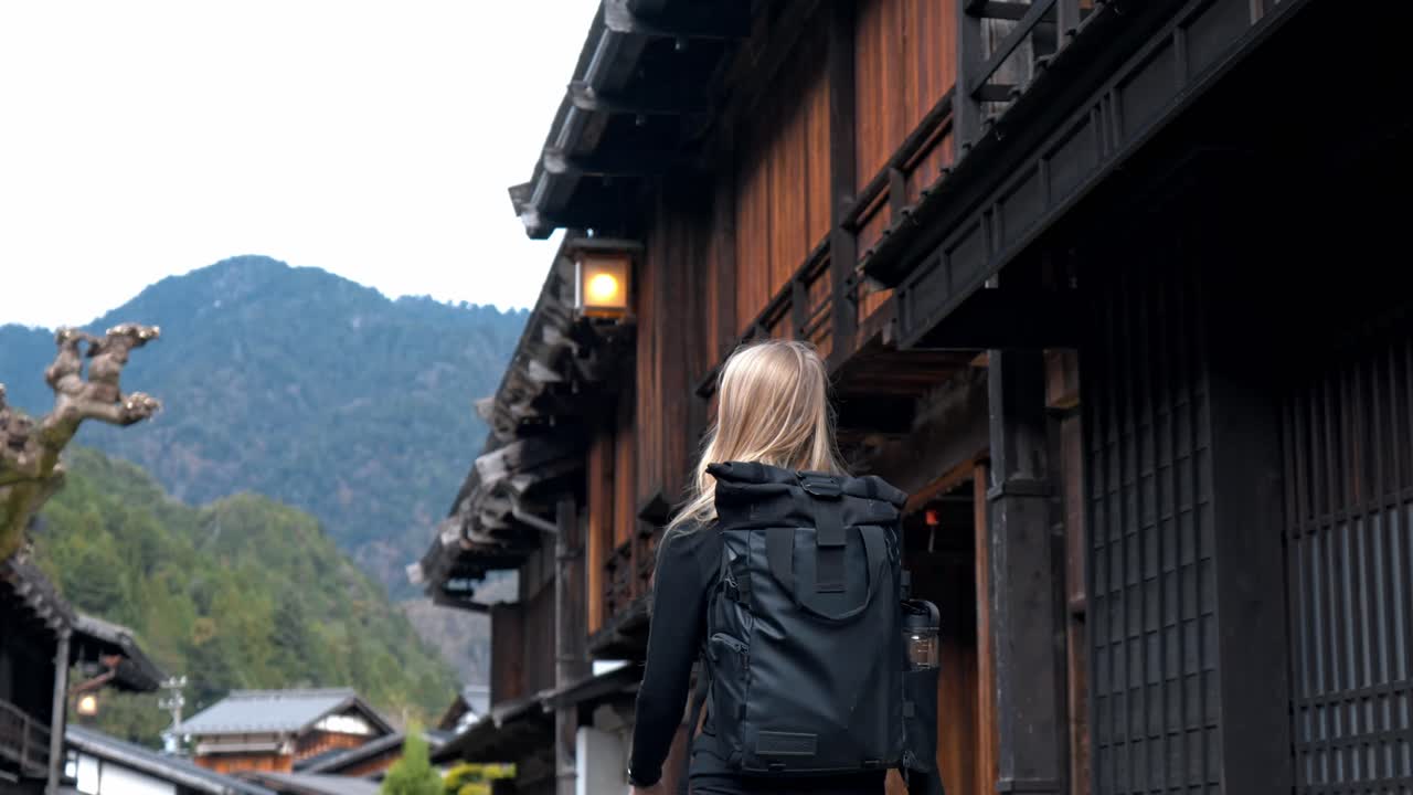 A young woman walks through the historic streets of Tsumago, a preserved post town along the Nakasendo Trail in Japan.