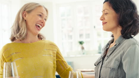 same sex mature female couple with credit card using digital tablet at home to book holiday or shop