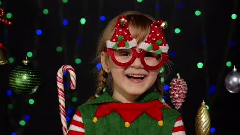 Kid-girl-in-Christmas-elf-Santa-helper-costume-dancing,-fooling-around.-New-Year-holiday-celebration