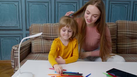 Lovely-mother-babysitter-teacher-helping-kid-daughter-with-homework,-learning-drawing-at-home