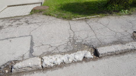 deteriorating gray asphalt footpath, disappeared verges, potholes in road, poor public maintenance by government