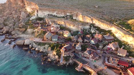 Wooden-Popeye-Village-on-rocky-sea-coastline,-aerial-view