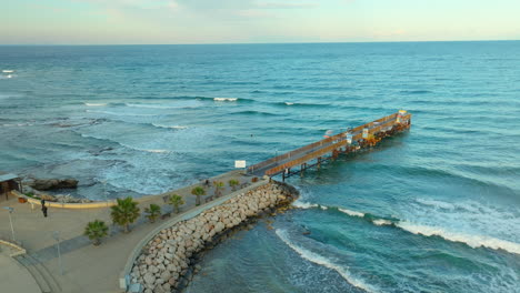 Vista-Aérea-De-Un-Muelle-De-Madera-En-Protaras,-Chipre,-Con-Mar-Ondulado.