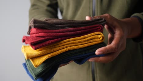 persona que sostiene una pila de calcetines de colores