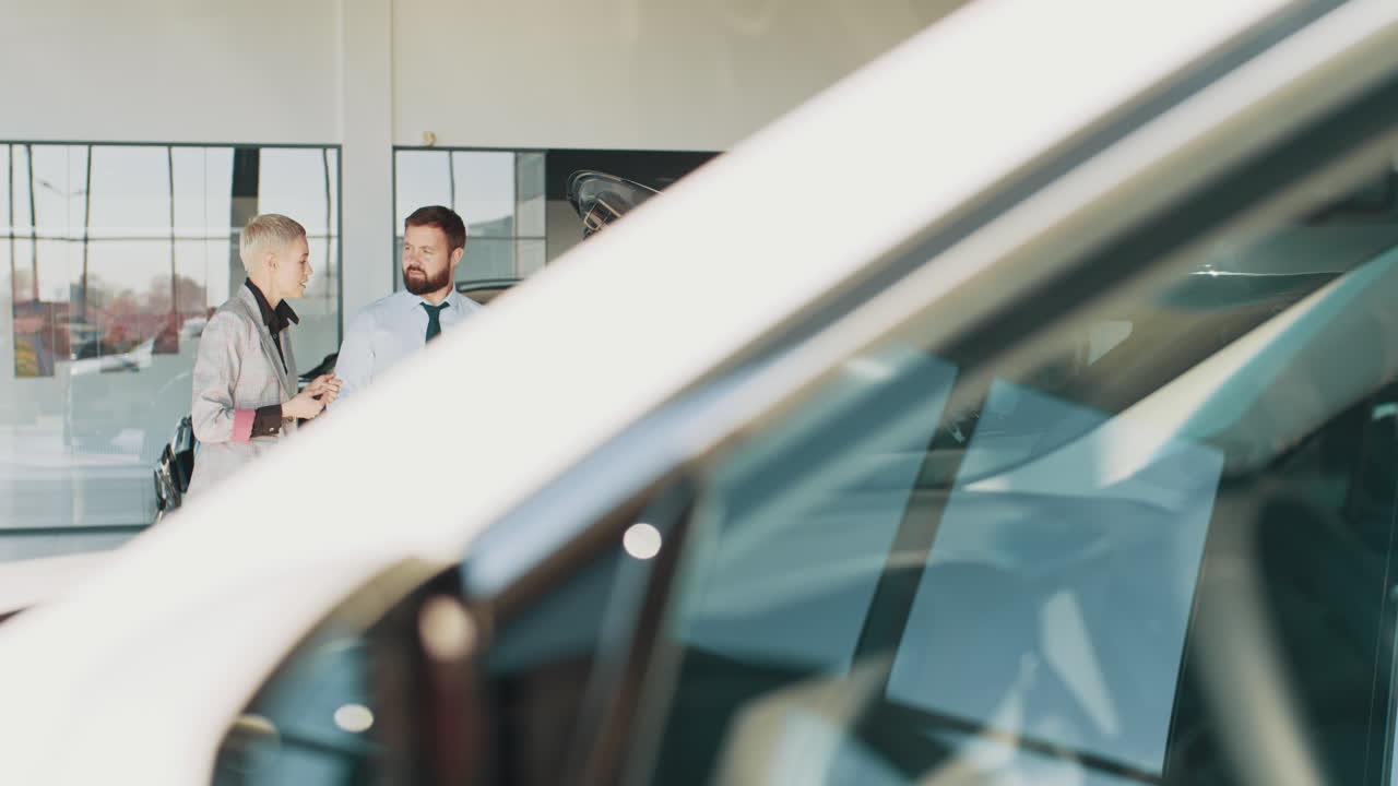 vendedor de automóviles discutiendo el vehículo con el cliente en la sala de exposiciones