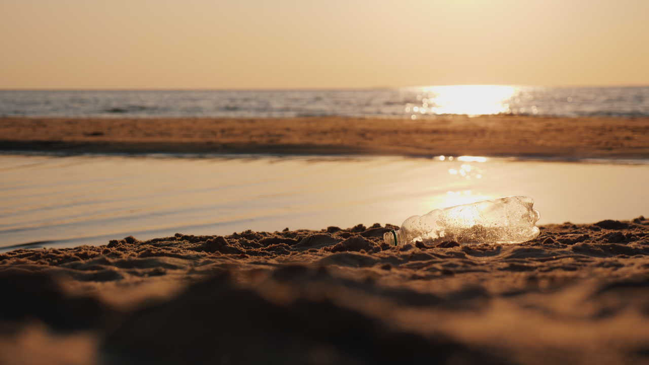 el hombre recoge una botella de plástico vacía en la playa cuidando el medio ambiente