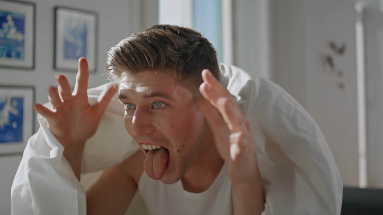 Closeup funny guy laughing in home morning. Cheerful boyfriend making grimace