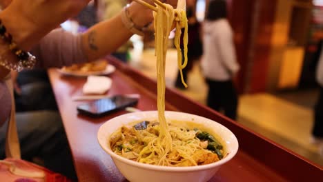 person enjoying noodles with chopsticks in melbourne