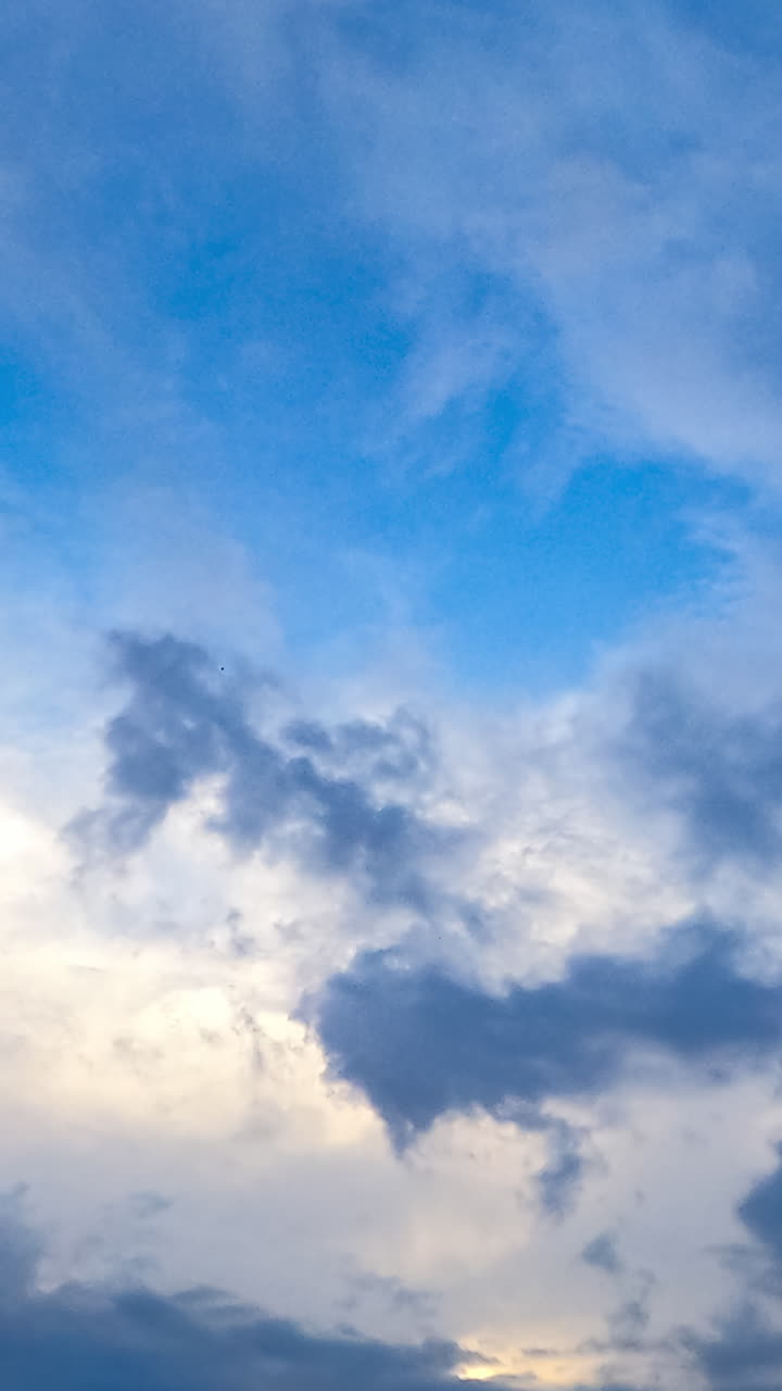 Amazing light clouds appearing in the sky. Timelapse of quick cloud transformation. Low angle view. Vertical video