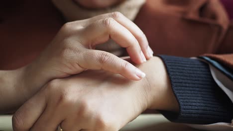 close up of a woman's hands touching her wrist