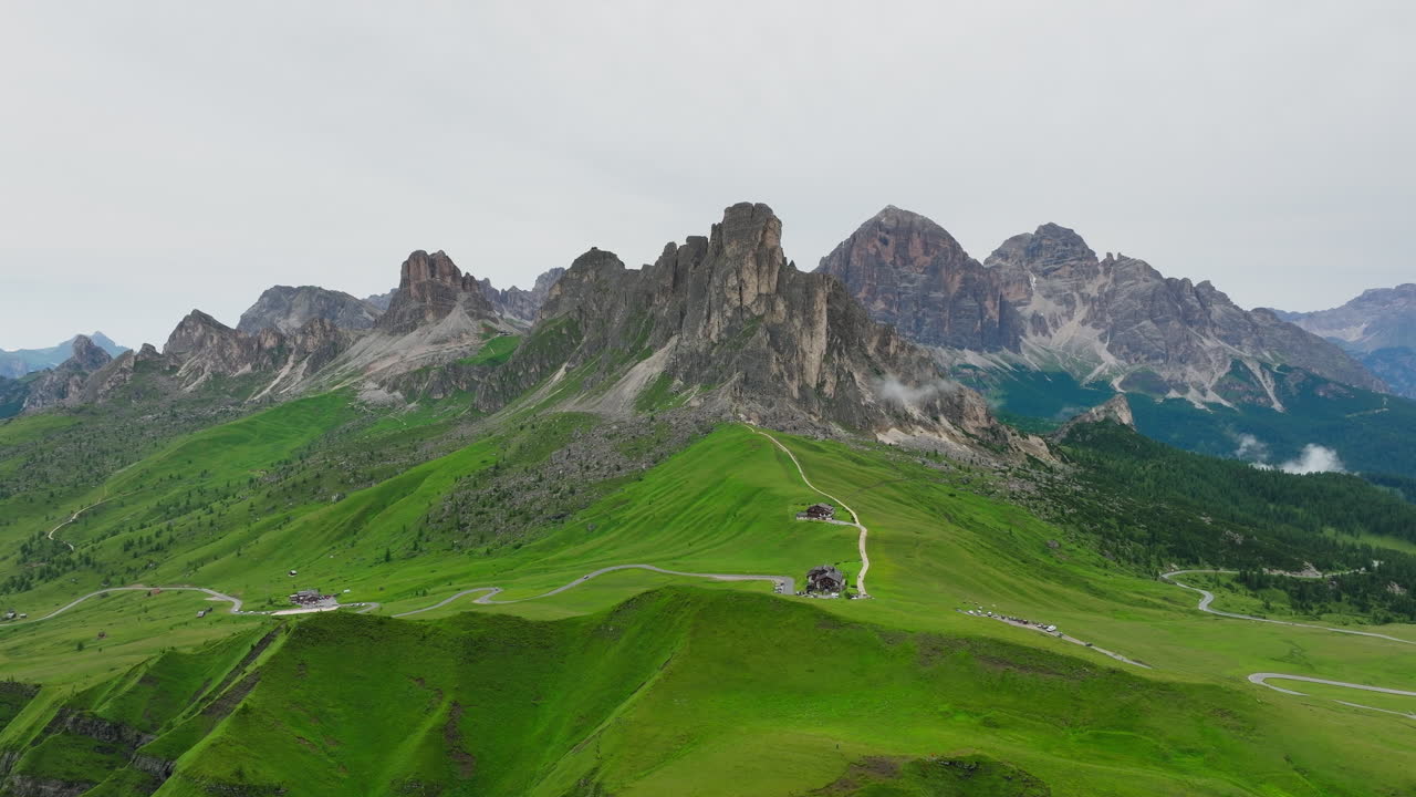 Tracking left across jagged peaks at Giau Pass in Dolomites with green summer slopes