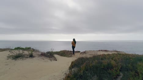 mujer de pie en el acantilado costero en el pacífico tomando fotos con el teléfono hacia adelante dolly rápido