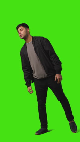 vertical video full length portrait shot of man walking into frame and waiting standing against green screen