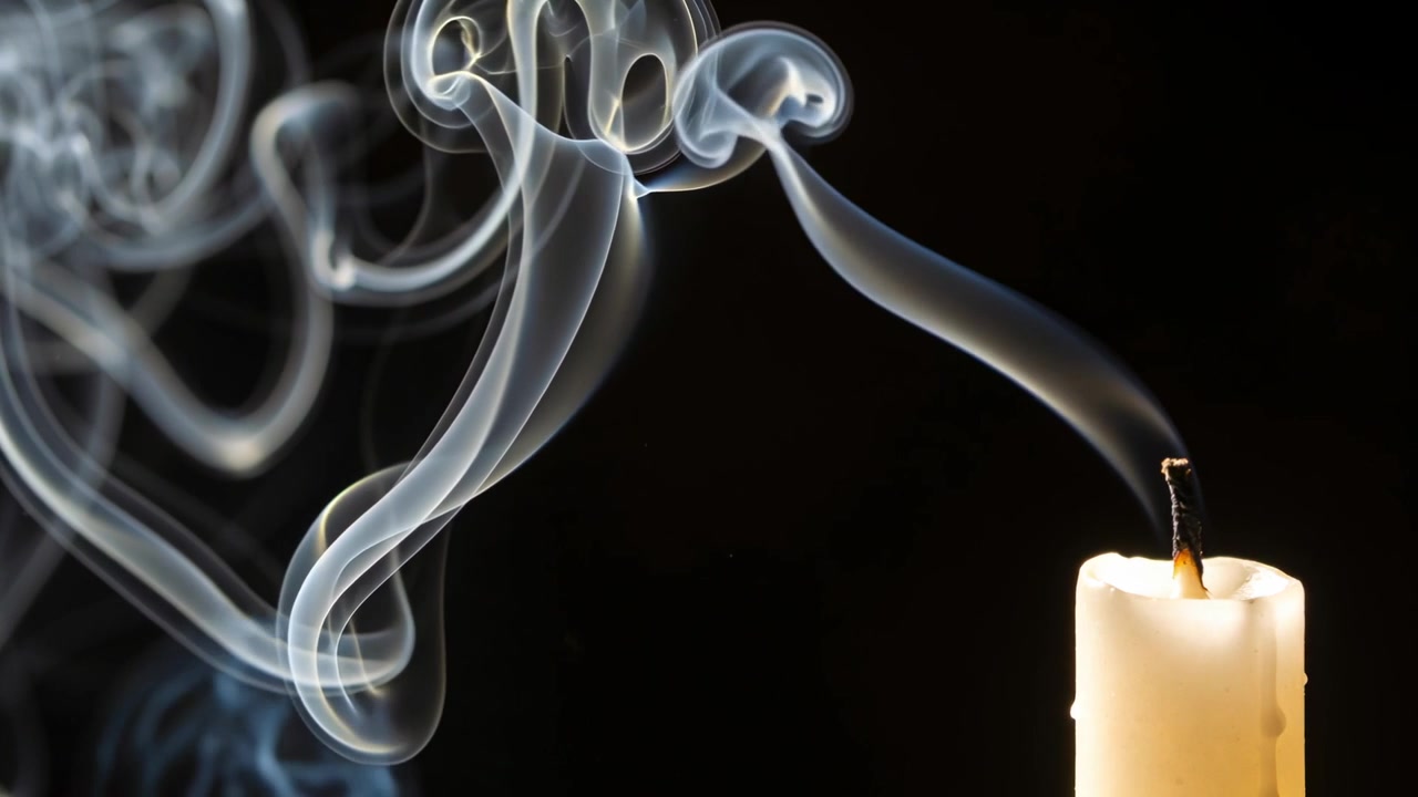 Rising cream candle's gray smoke drifting after snuffing charred wick in dark studio with wax drips