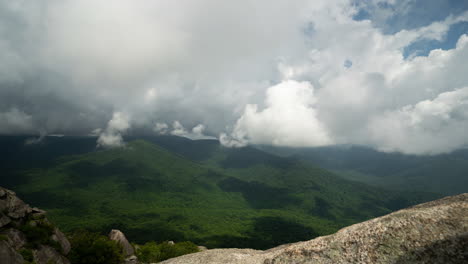 time lapse of big, white, puffy clouds growing and moving in the wind above wide open green mountains and valleys