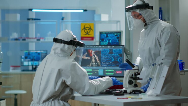Chemist woman in ppe suit typing on pc checking virus development