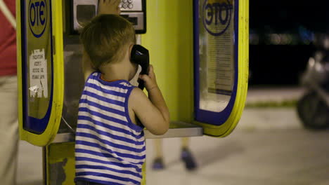 young boy talking to the phone in a booth