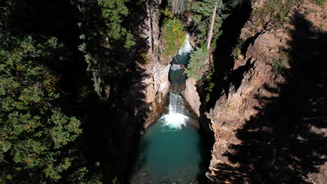 Cascade-Creek-Falls,-Colorado-USA,-Aerial-View-of-Waterfalls-and-Natural-Pool-Under-Steep-Canyon-Cliffs