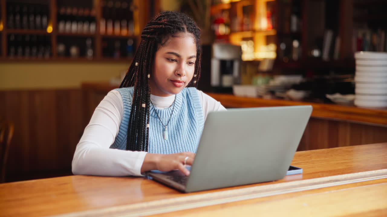 Woman working on a laptop at a bar