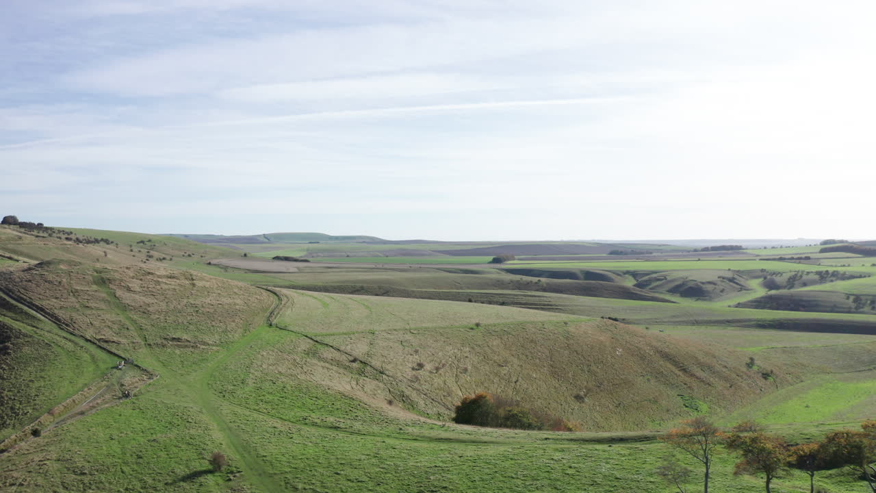 вид с воздуха на холмы и поля в английской сельской местности, снятый в яркий осенний день с ярко-голубым небом