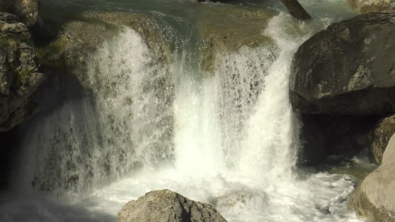 Small waterfall of rushing water over rocks in mountain river, slow ...