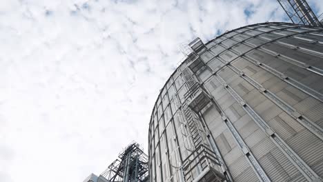 metal granaries of a modern agricultural plant. large grain elevator under white sky. agribusiness concept. view from below