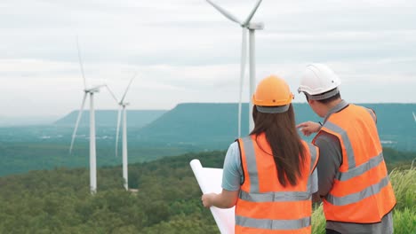 progressive concept of engineers working in the wind farm atop of the mountain.