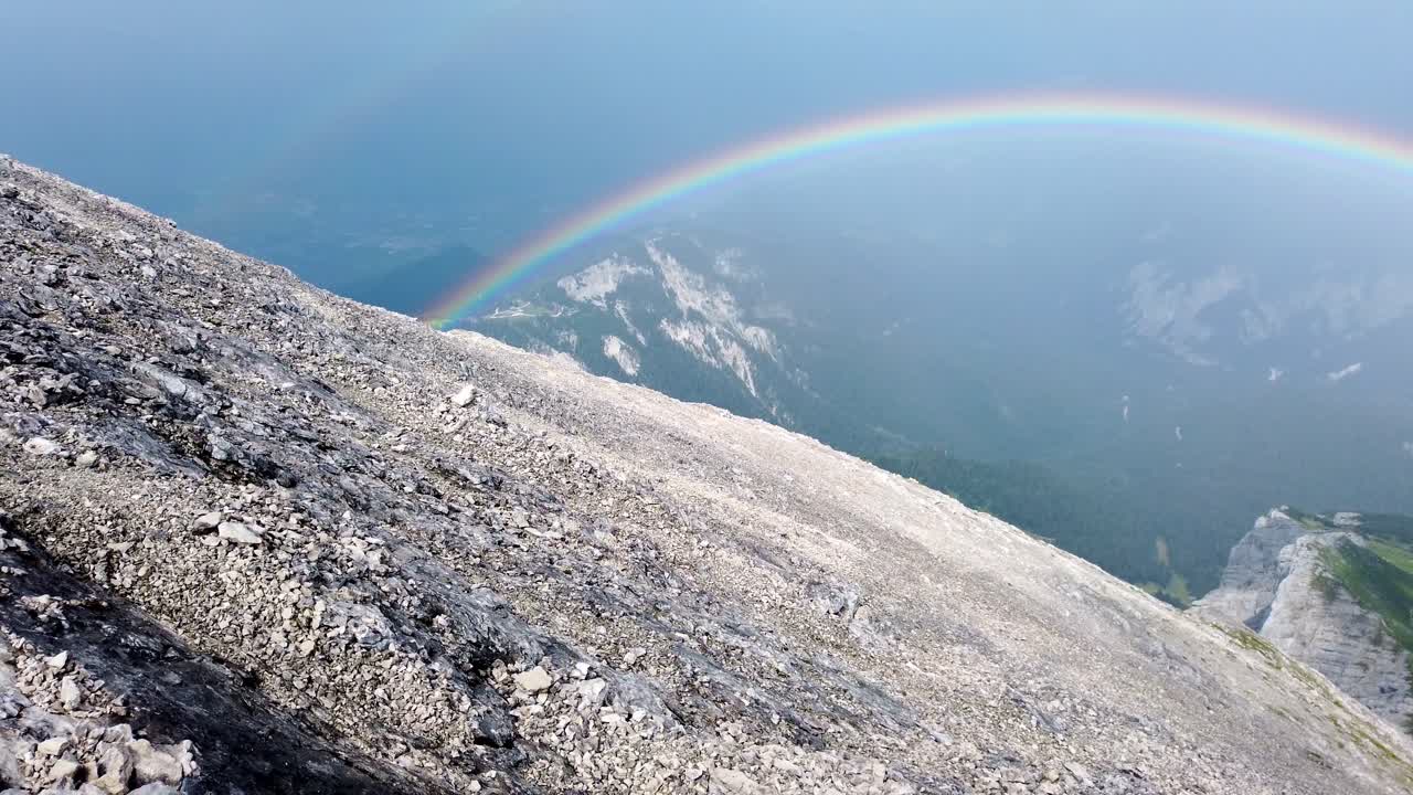 panorámica lenta de derecha a izquierda sobre un campo de grava alpino en los alpes alemanes que muestra un arco iris doble justo después de una tormenta