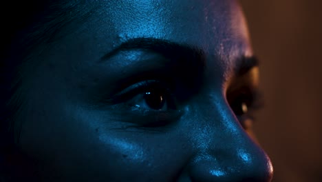 woman lit by blue light smiling at a screen