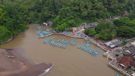 aerial view of rows of blue fishing boats anchored in the harbour with brown sea water