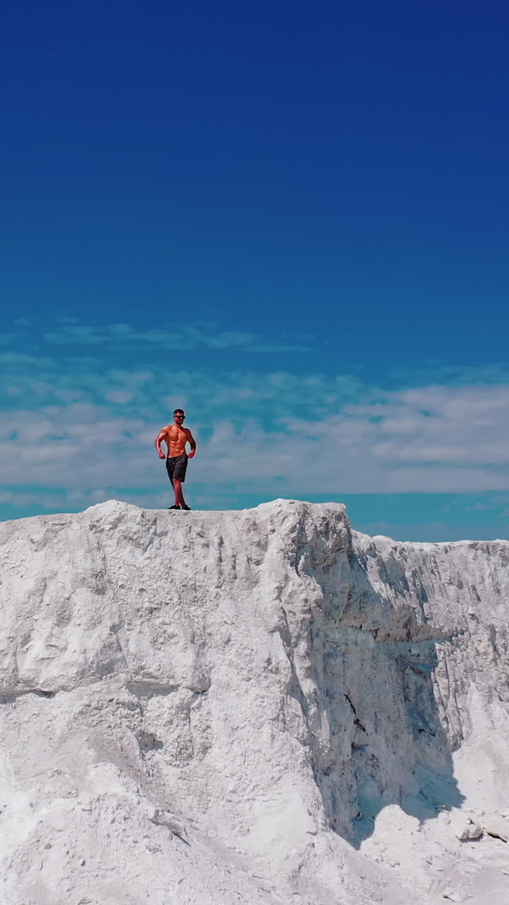 Professional bodybuilder posing outdoors. Concept of beautiful healthy body. Aerial view Vertical video
